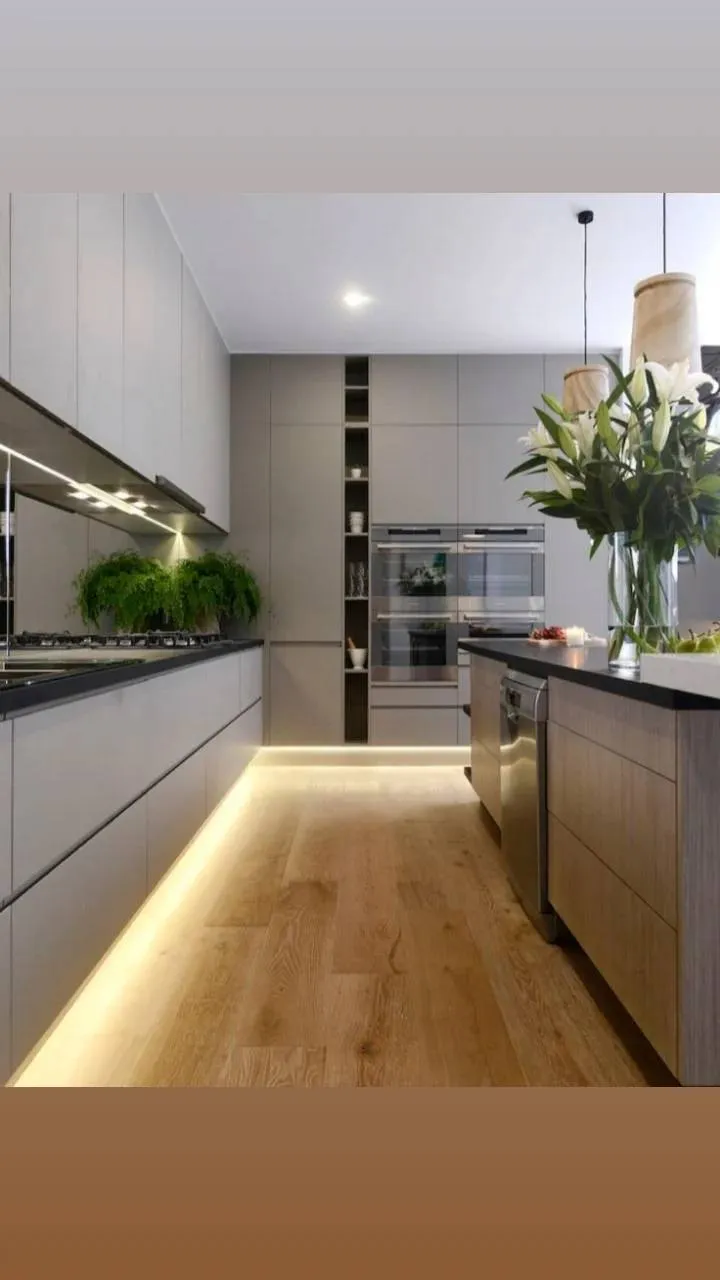 Modern white kitchen with island and integrated appliances.